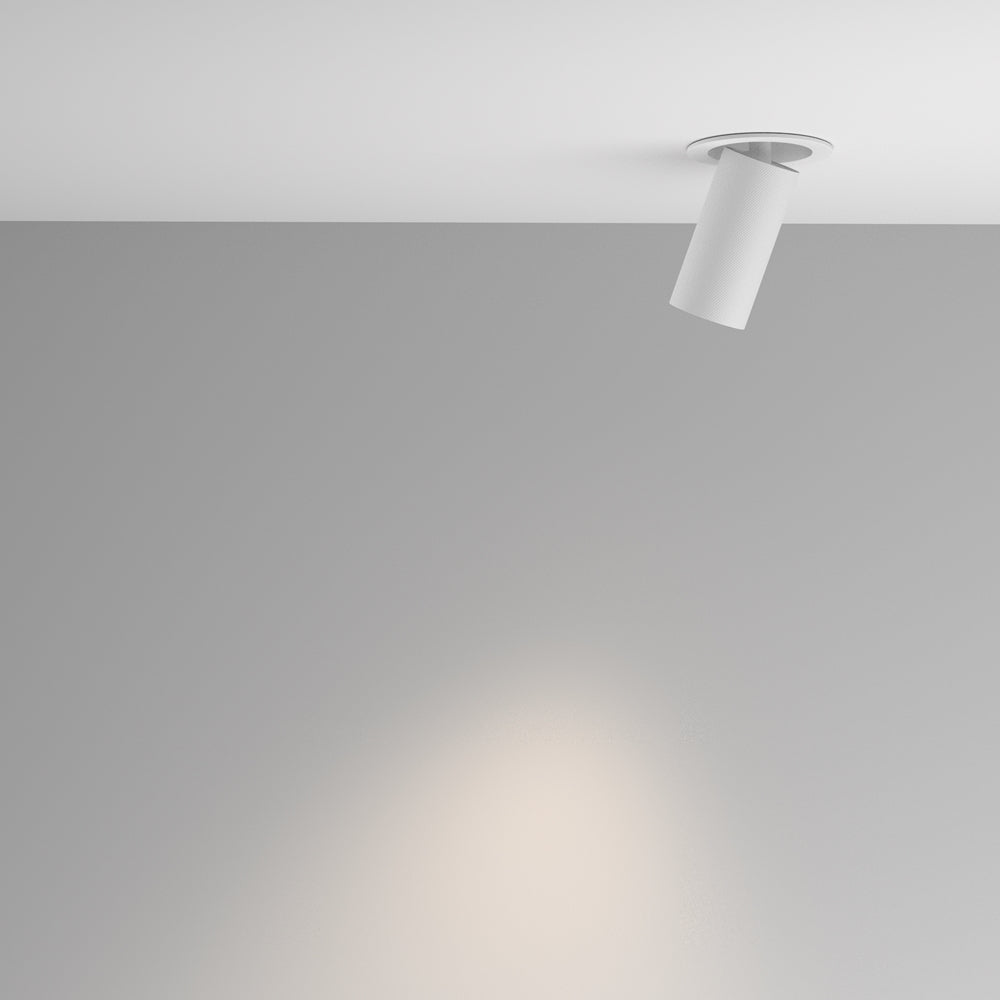 Mise en ambiance d'un spot blanc au plafond projetant un faisceau lumineux chaud sur le mur.