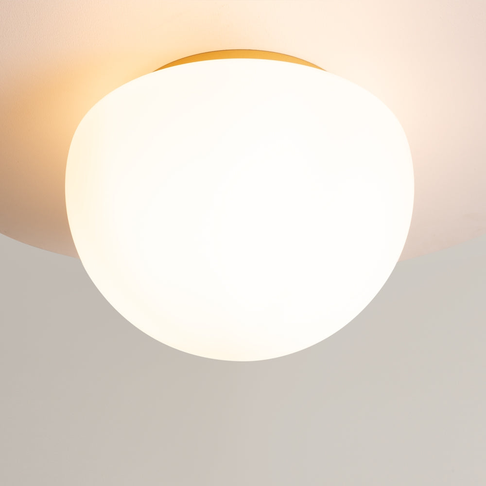Gros plan sur le diffuseur allumé, halo de lumière chaude sur plafond beige.