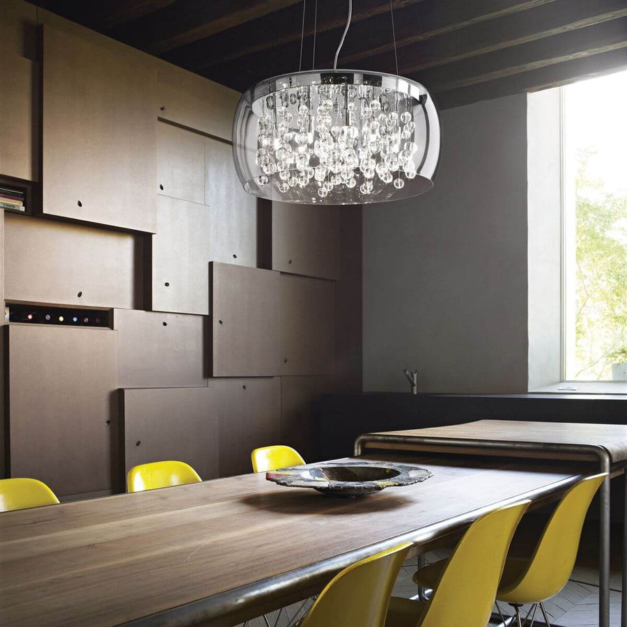 Suspension allumée au-dessus d'une table en bois, intérieur avec chaises jaunes et mur de panneaux.