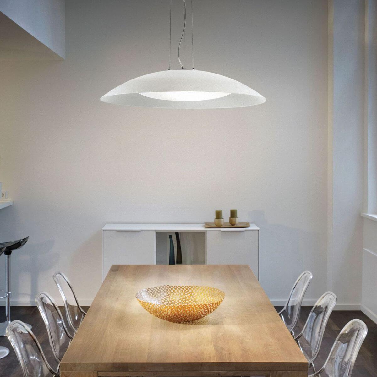 Suspension allumée au-dessus d'une table en bois dans une salle à manger moderne.