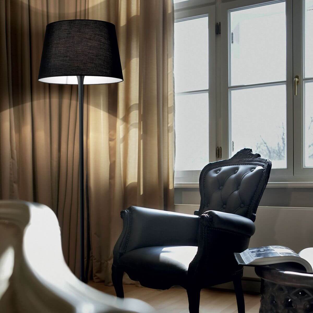 Mise en ambiance dans un salon avec fauteuil capitonné, rideaux beiges et fenêtre.