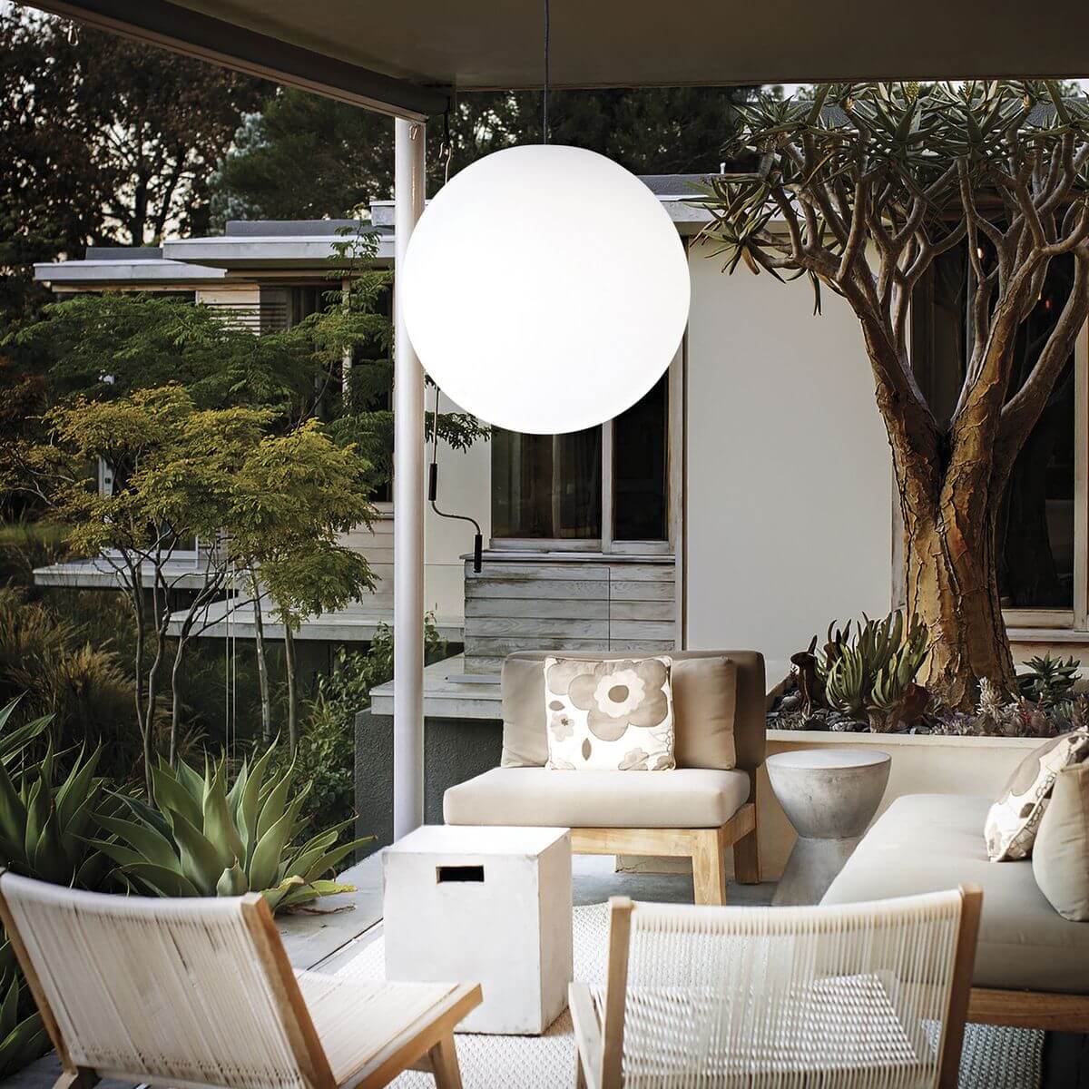Mise en ambiance sur terrasse couverte, grande sphère lumineuse suspendue au-dessus du salon