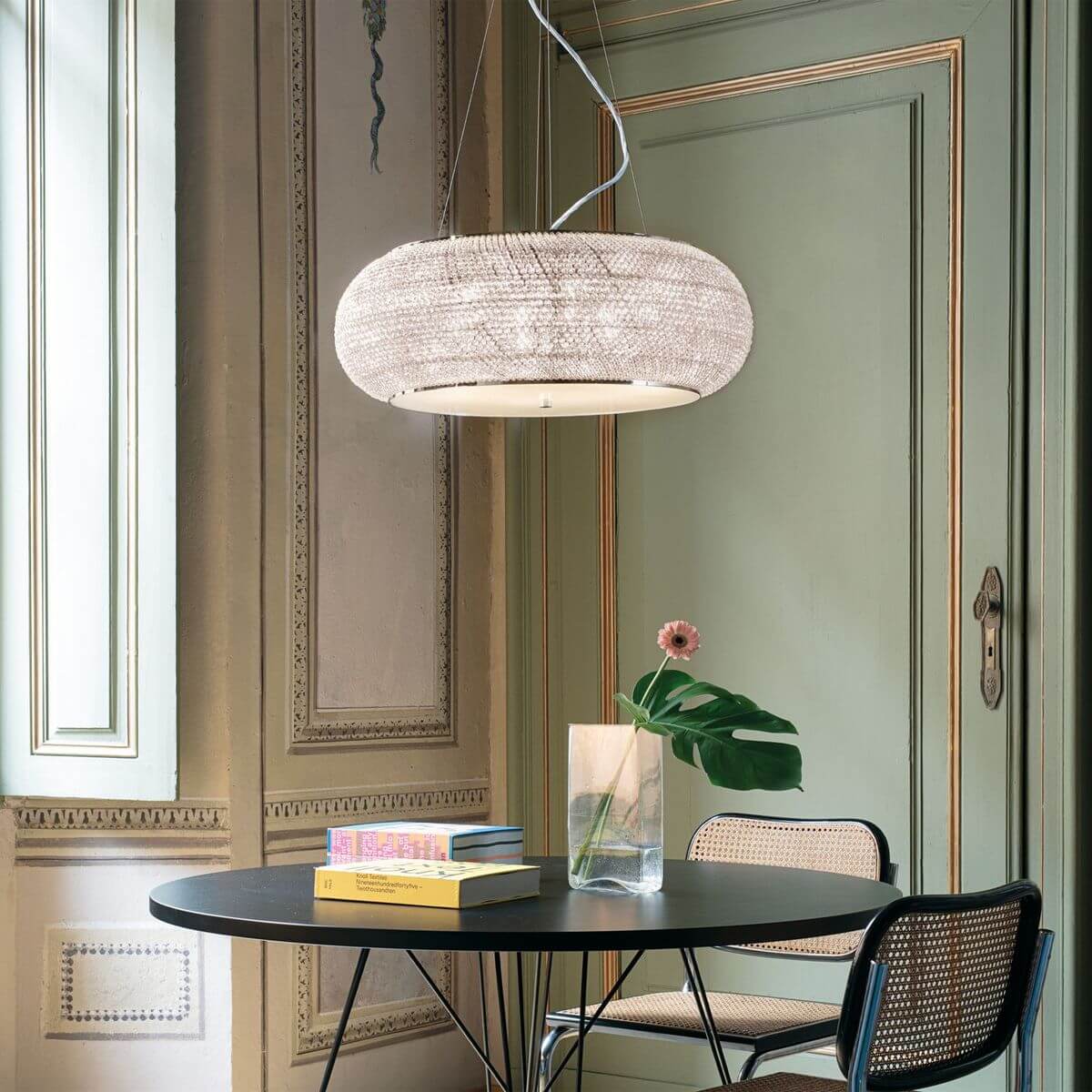 Suspension installée au-dessus d'une table ronde dans un intérieur vert et beige.