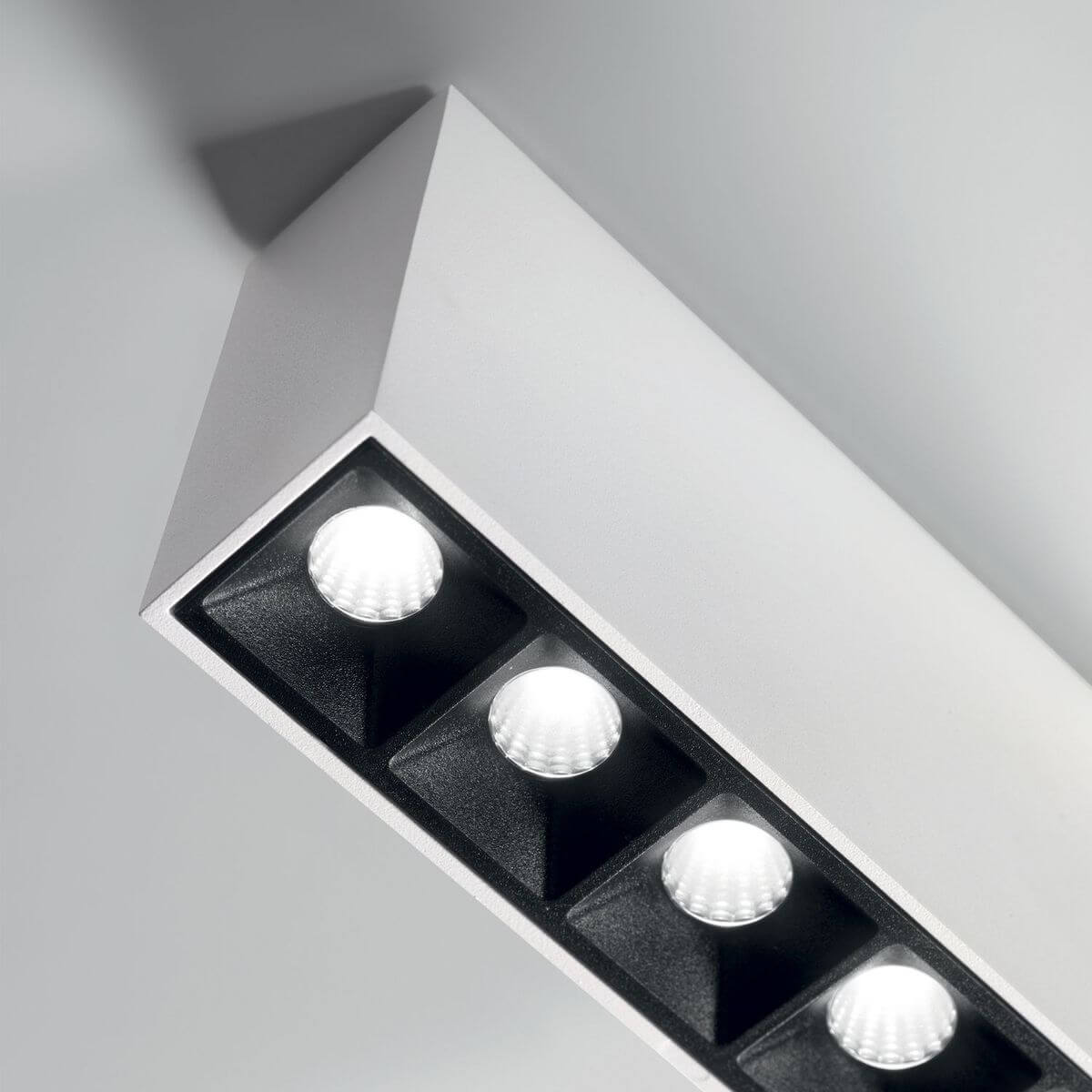 Vue rapprochée du plafonnier blanc avec quatre projecteurs LED noirs alignés