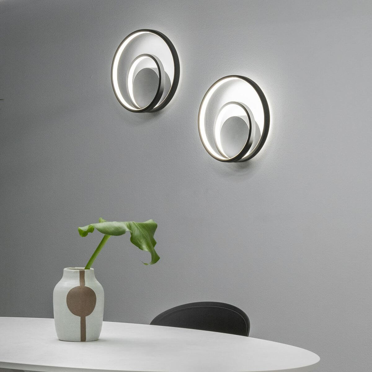 Mise en ambiance avec deux appliques murales allumées fixées sur un mur gris