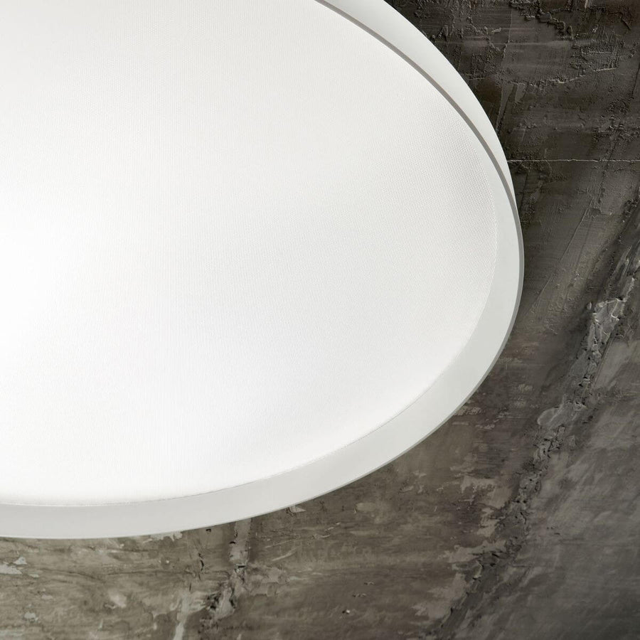 Détail de finition : diffuseur blanc texturé et cerclage mince, posé sur fond béton