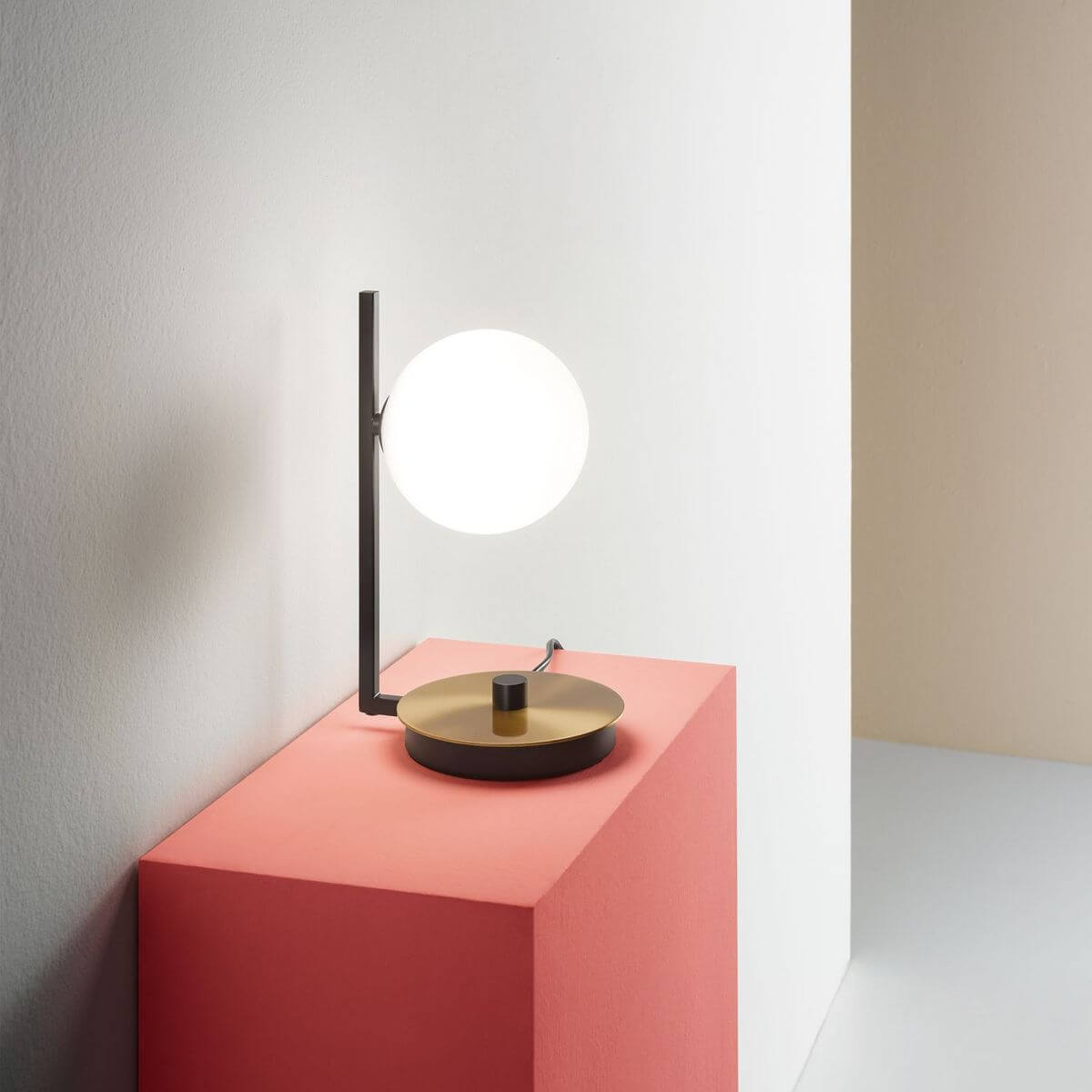Lampe allumée sur un socle rose dans une mise en ambiance minimaliste.