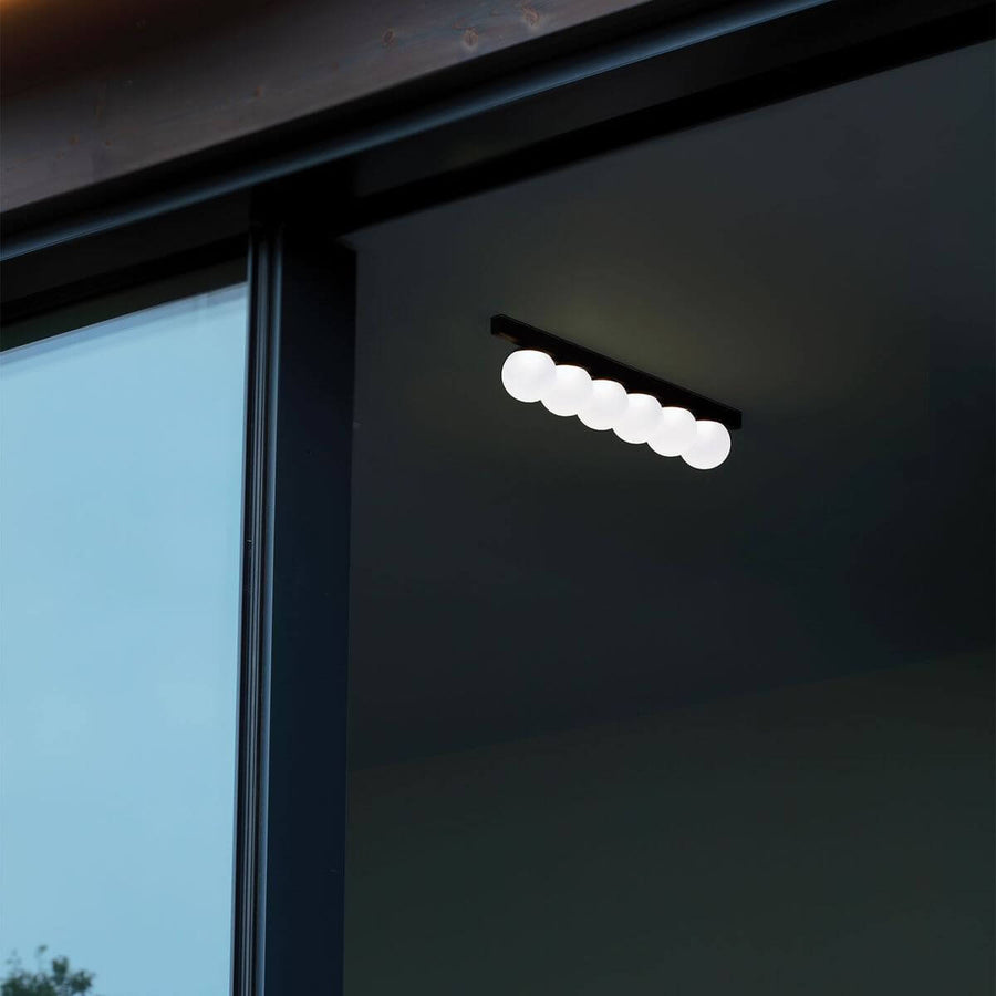 Plafonnier noir allumé sous un plafond sombre près d'une fenêtre.