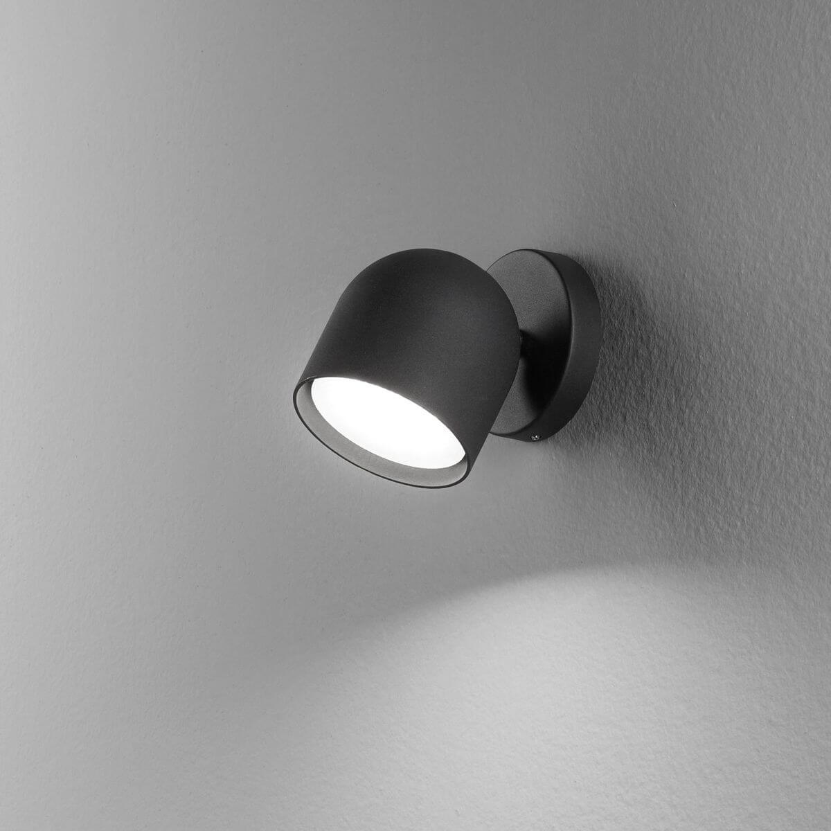 Mise en ambiance murale, applique noire allumée projetant une lumière douce vers le bas