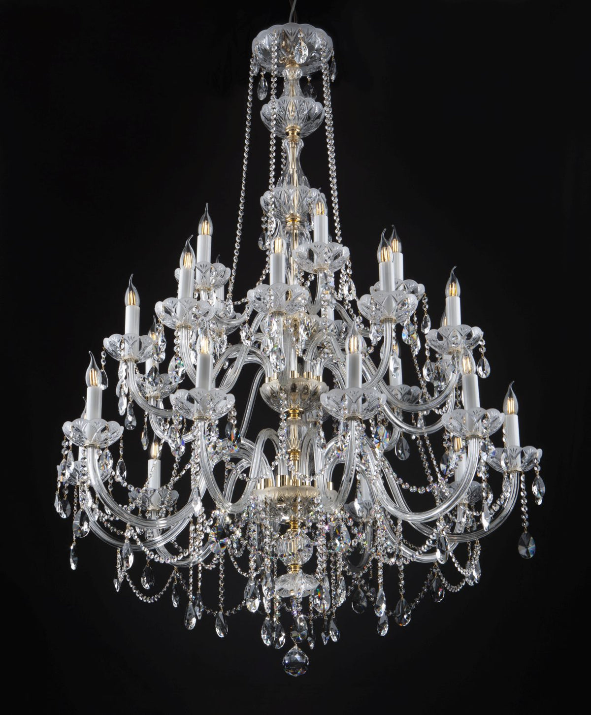 Lustre en cristal suspendu, de face, sur fond noir, avec ses bras et pampilles.
