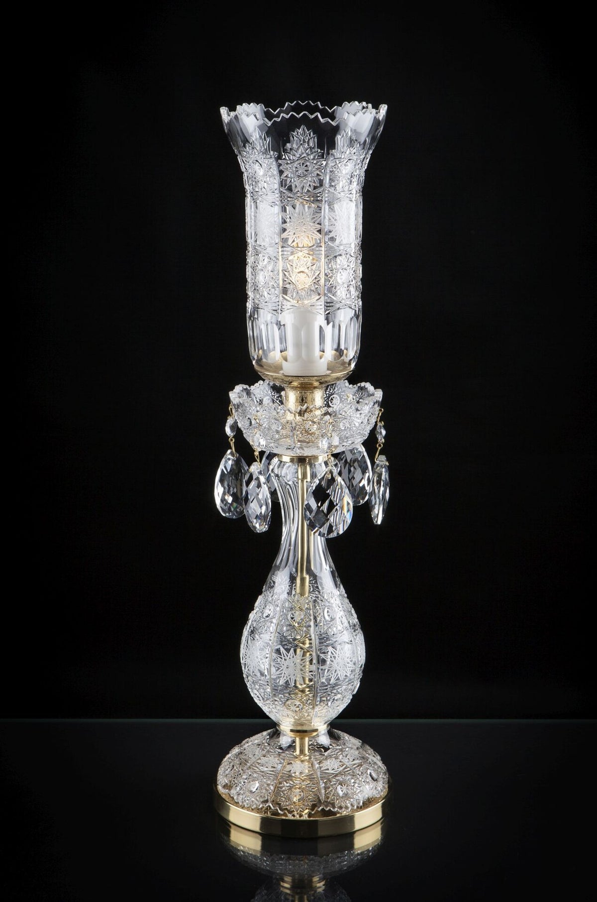 Lampe à poser en cristal taillé, abat-jour cylindrique et pampilles, vue de face sur fond noir.