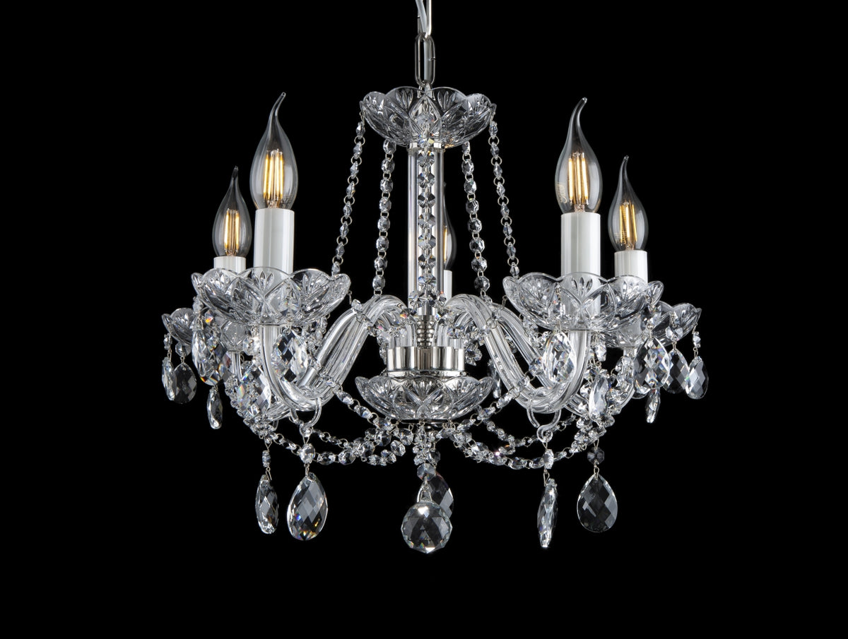 Lustre en cristal à cinq bras vu de face sur fond noir, ampoules allumées