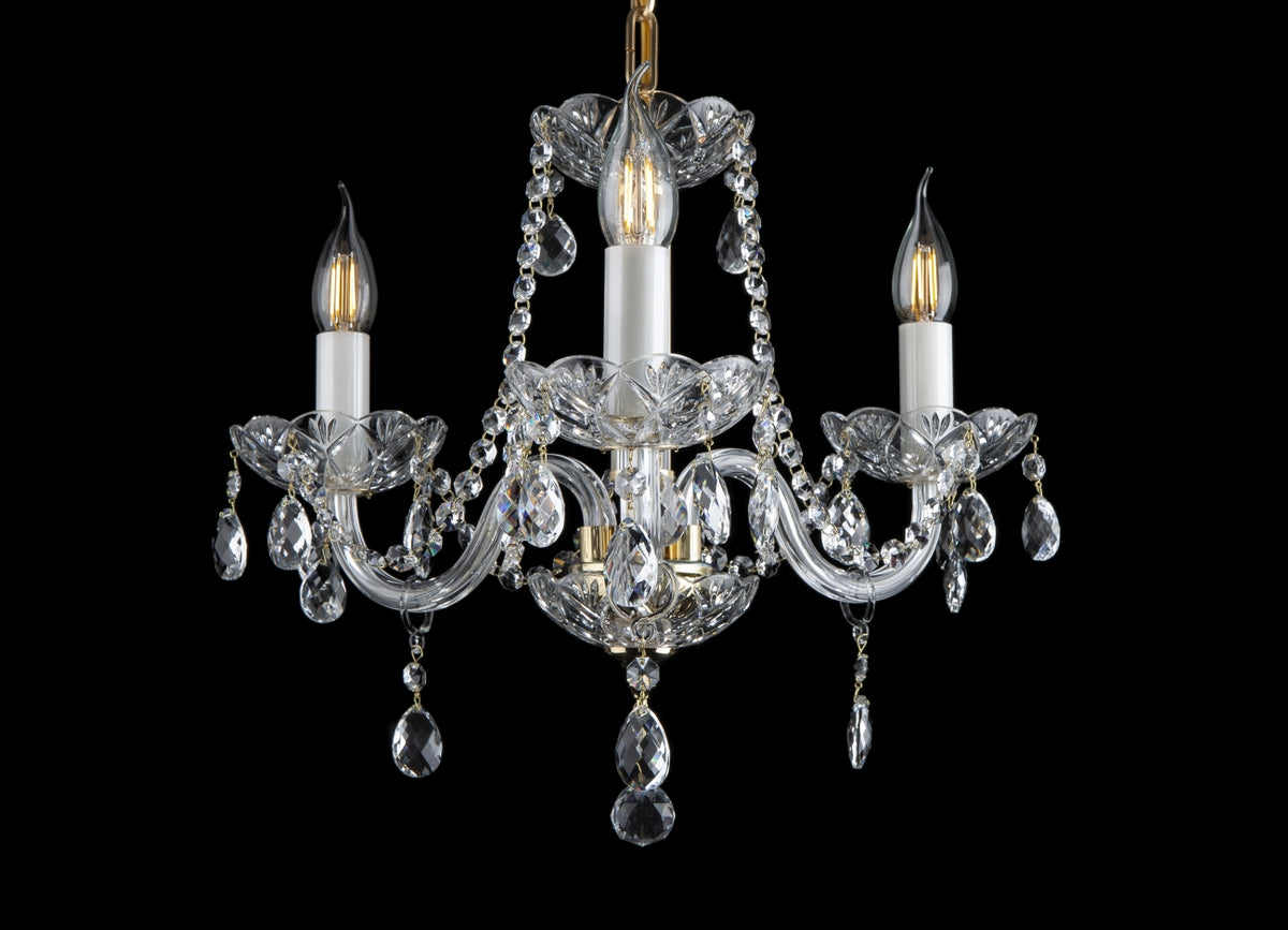 Lustre trois bras en cristal et métal doré, vue de face sur fond noir