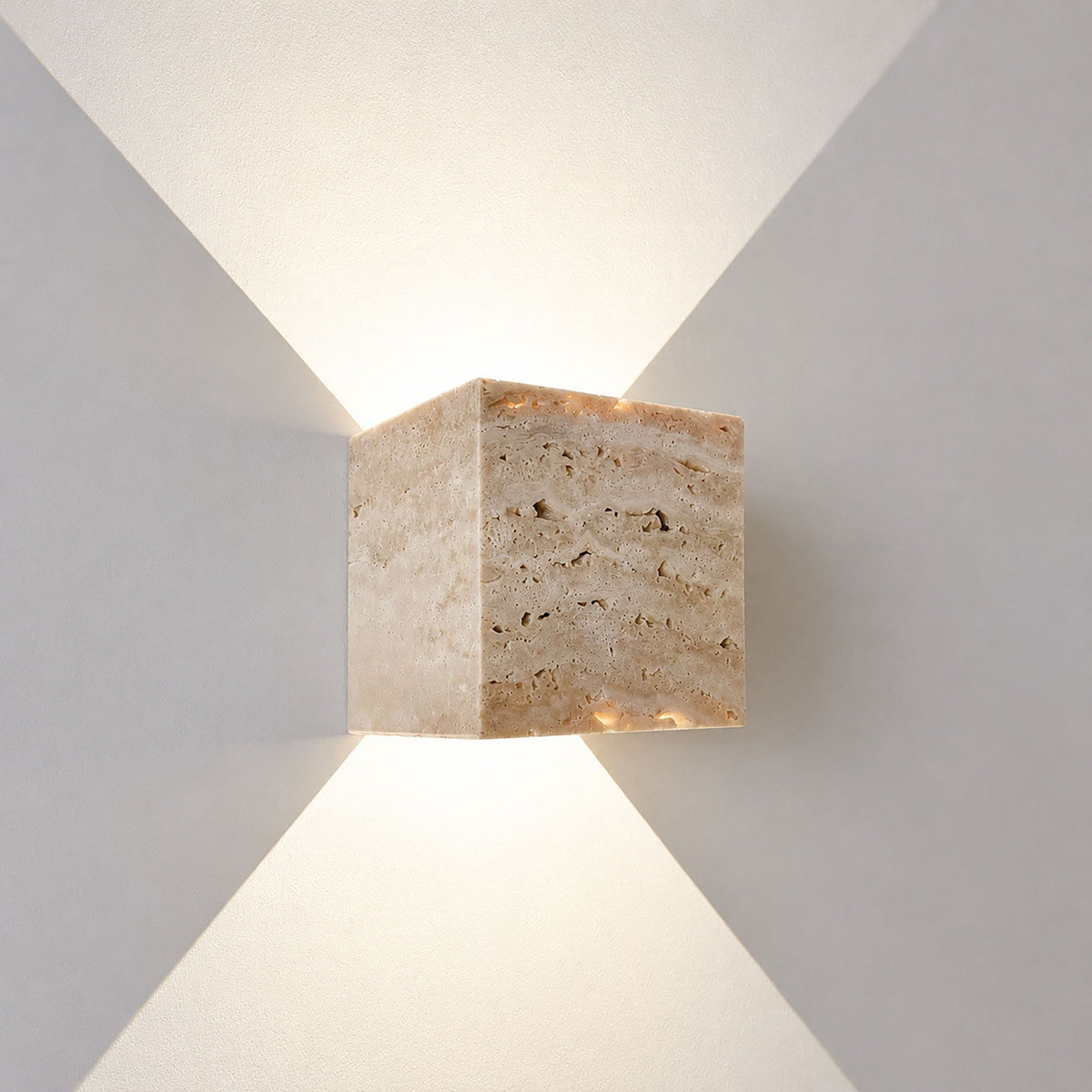 Gros plan de l'applique cube en travertin, texture poreuse et éclairage haut bas