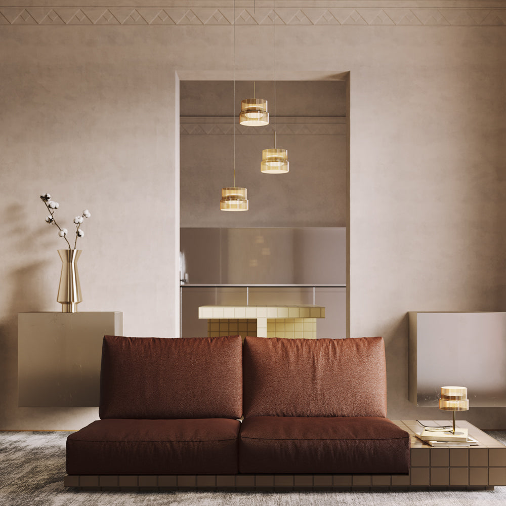 Mise en ambiance : salon beige avec canapé marron, lampe posée et suspensions dorées au fond.