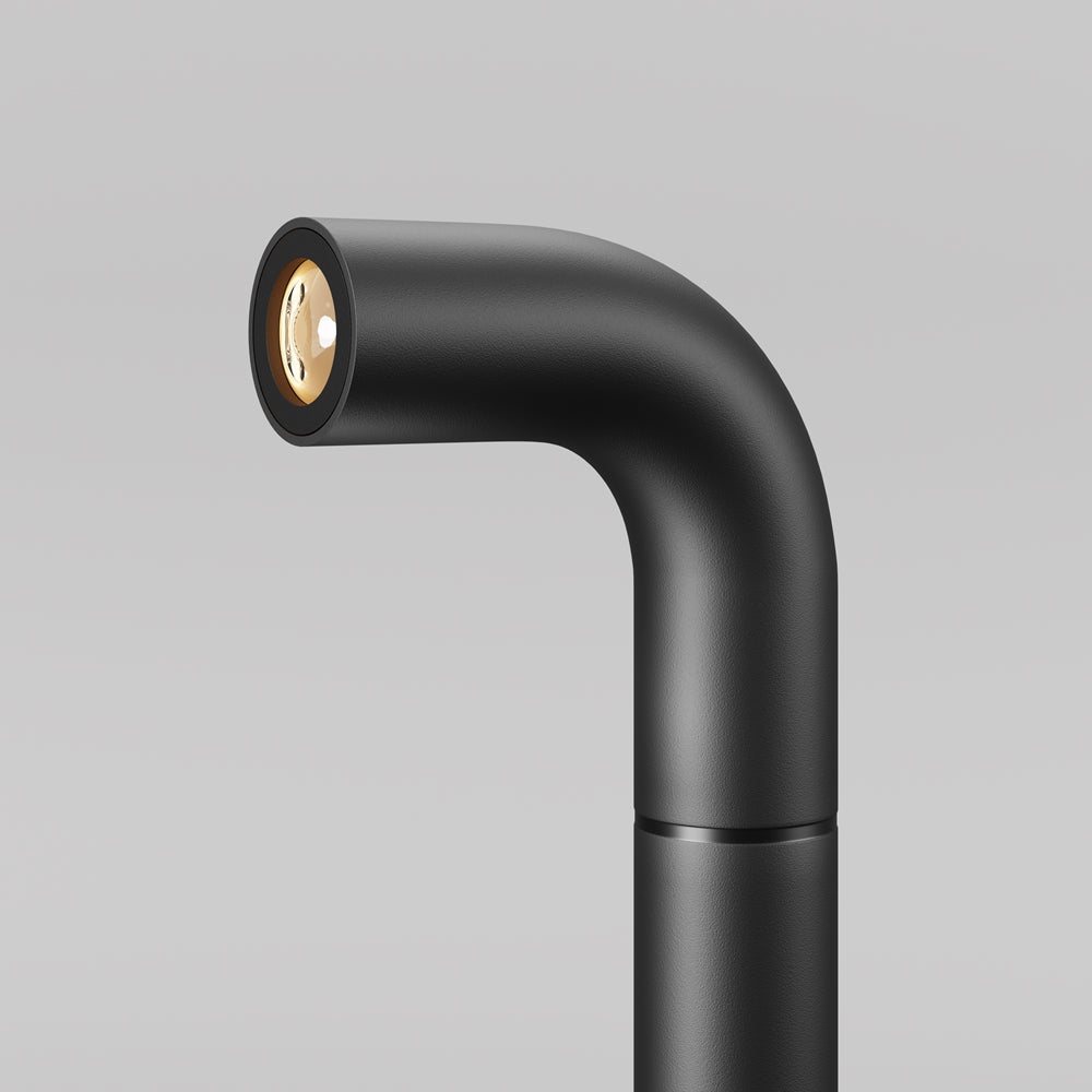 Gros plan sur la tête coudée et le réflecteur doré du luminaire noir mat.