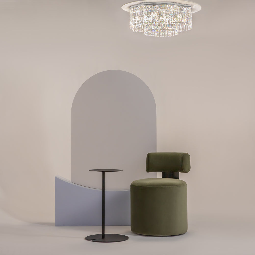 Mise en ambiance dans un salon avec fauteuil vert, table et miroir arche