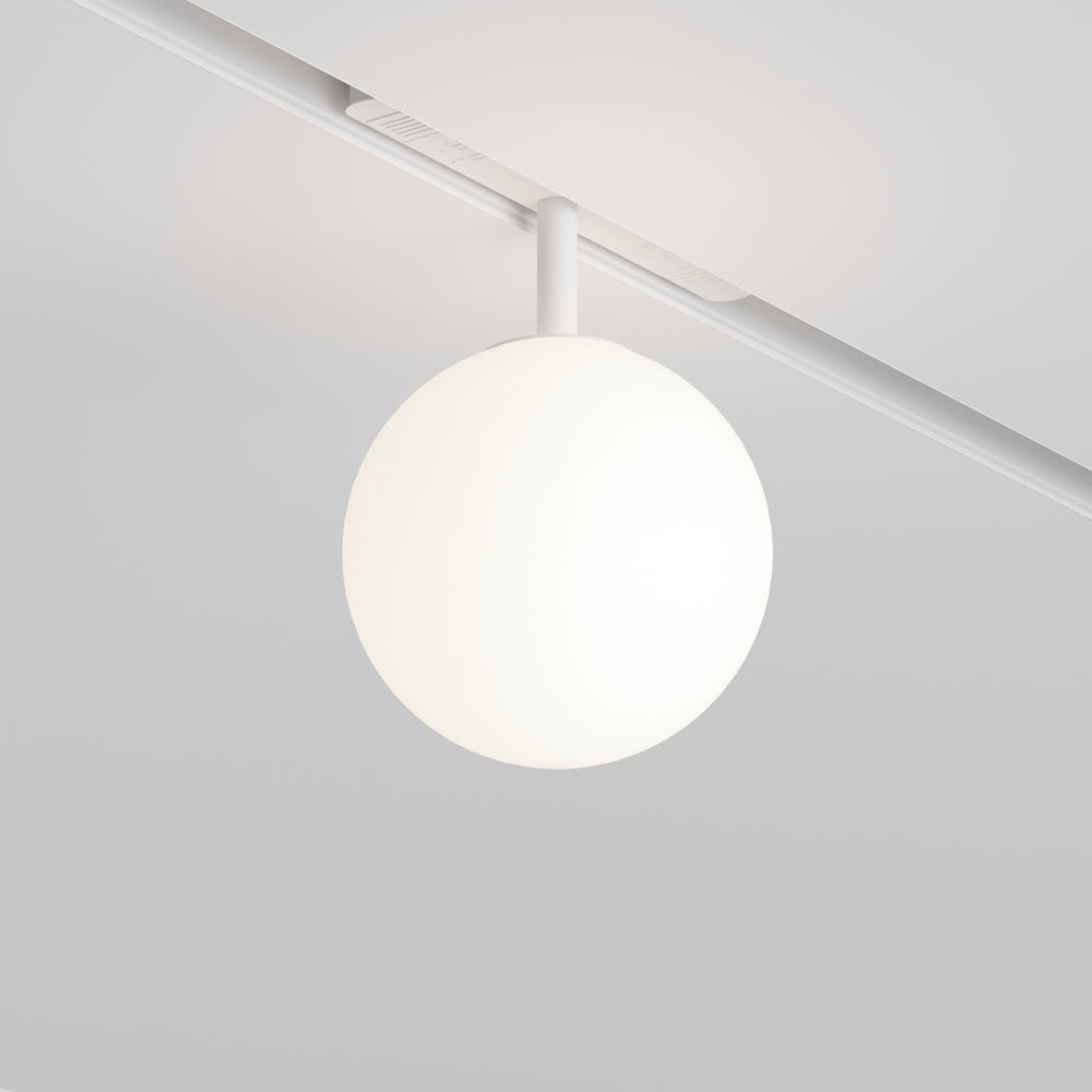 Luminaire sphérique blanc suspendu à un rail blanc fixé au plafond, éclairé.