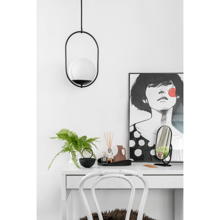 Suspension noire allumée au-dessus d'un bureau, avec cadre, livres et miroir.