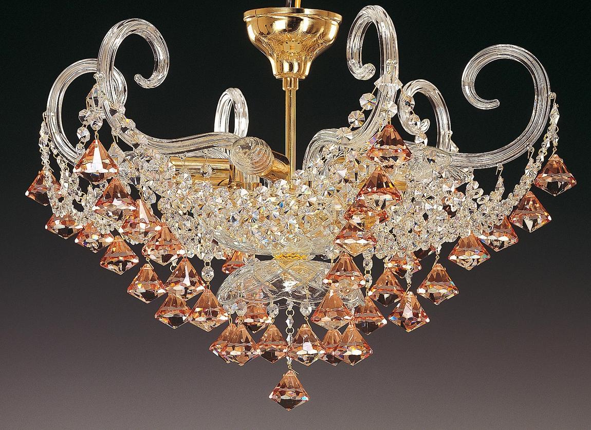 Lustre en cristal avec bras en verre recourbés et pendentifs ambrés sur fond noir.