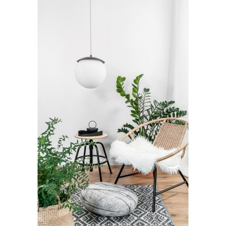 Mise en ambiance dans un salon lumineux avec fauteuil en rotin et plantes vertes