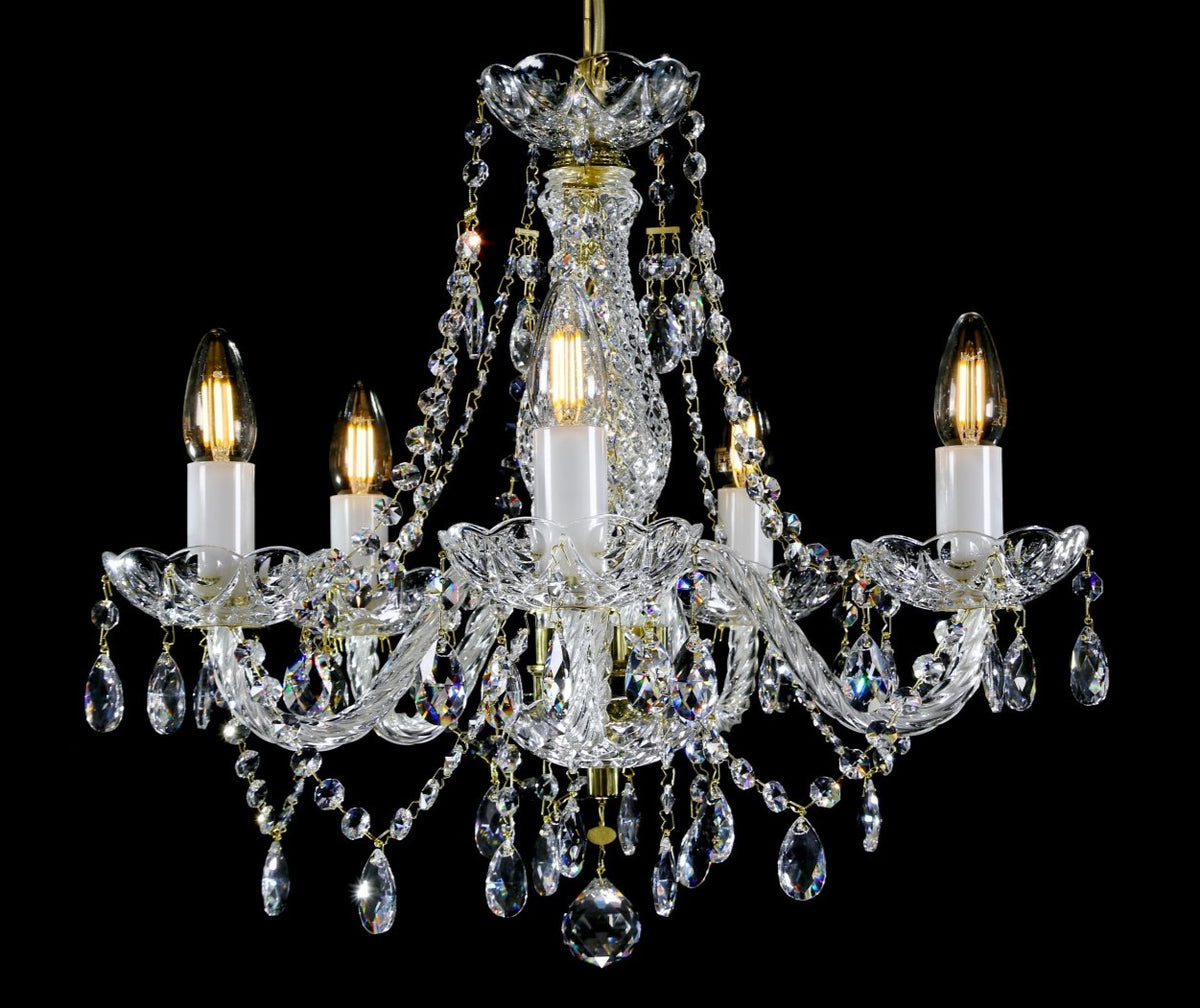 Lustre en cristal à cinq bras, ampoules allumées, suspendu sur fond noir uni