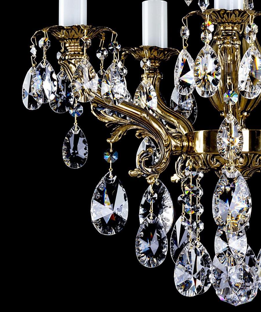 Gros plan sur les bras dorés recourbés et les gouttes de cristal du lustre