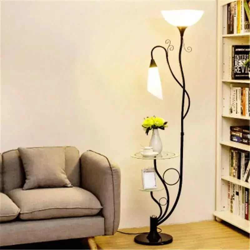 Lampadaire noir avec deux lumières et tablettes en verre devant un canapé et une bibliothèque