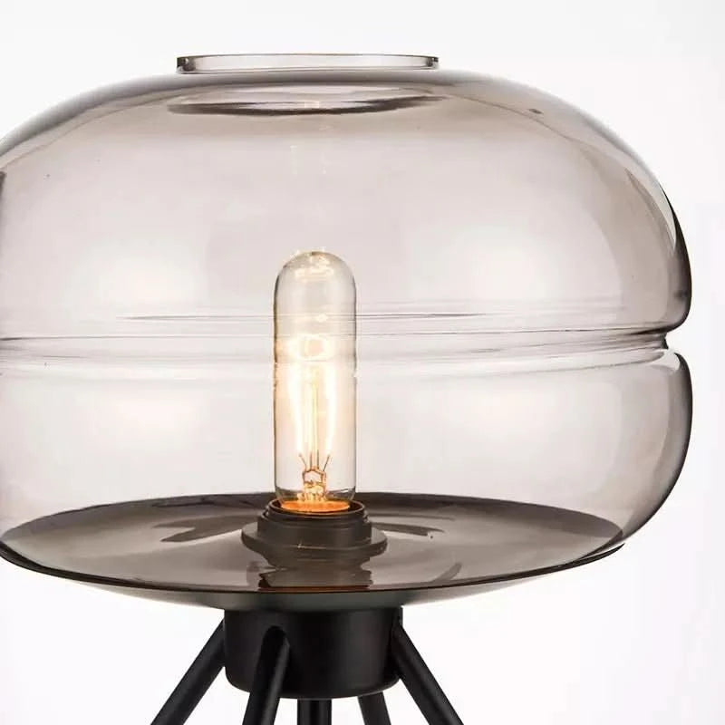 Gros plan sur l'abat-jour en verre et l'ampoule à filament allumée