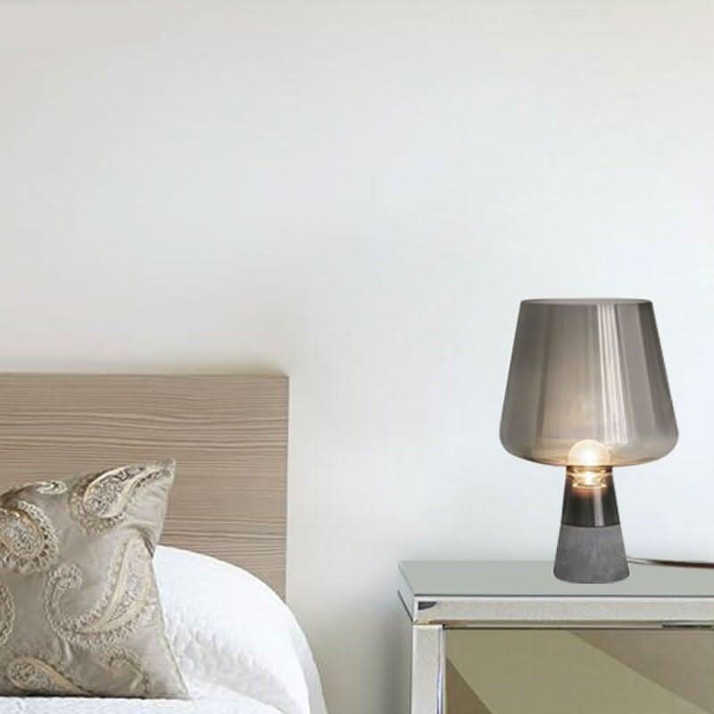 Mise en ambiance chambre, lampe posée sur table de chevet près d'un lit.