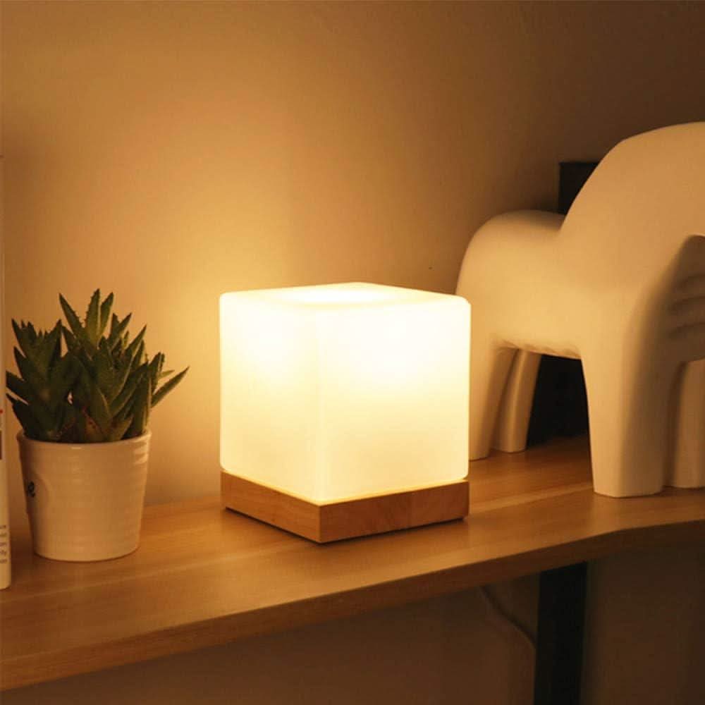 Lampe cube posée sur étagère en bois, allumée, près d'une plante grasse et d'une figurine.