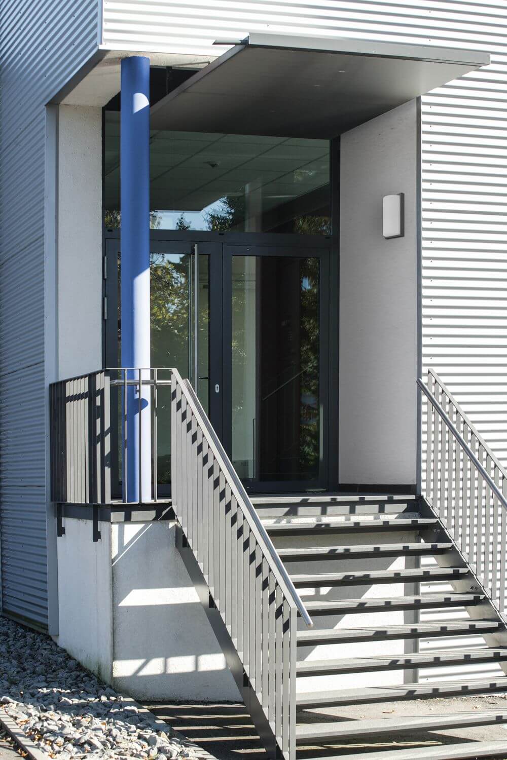 Mise en ambiance : applique posée près de la porte vitrée, escalier extérieur