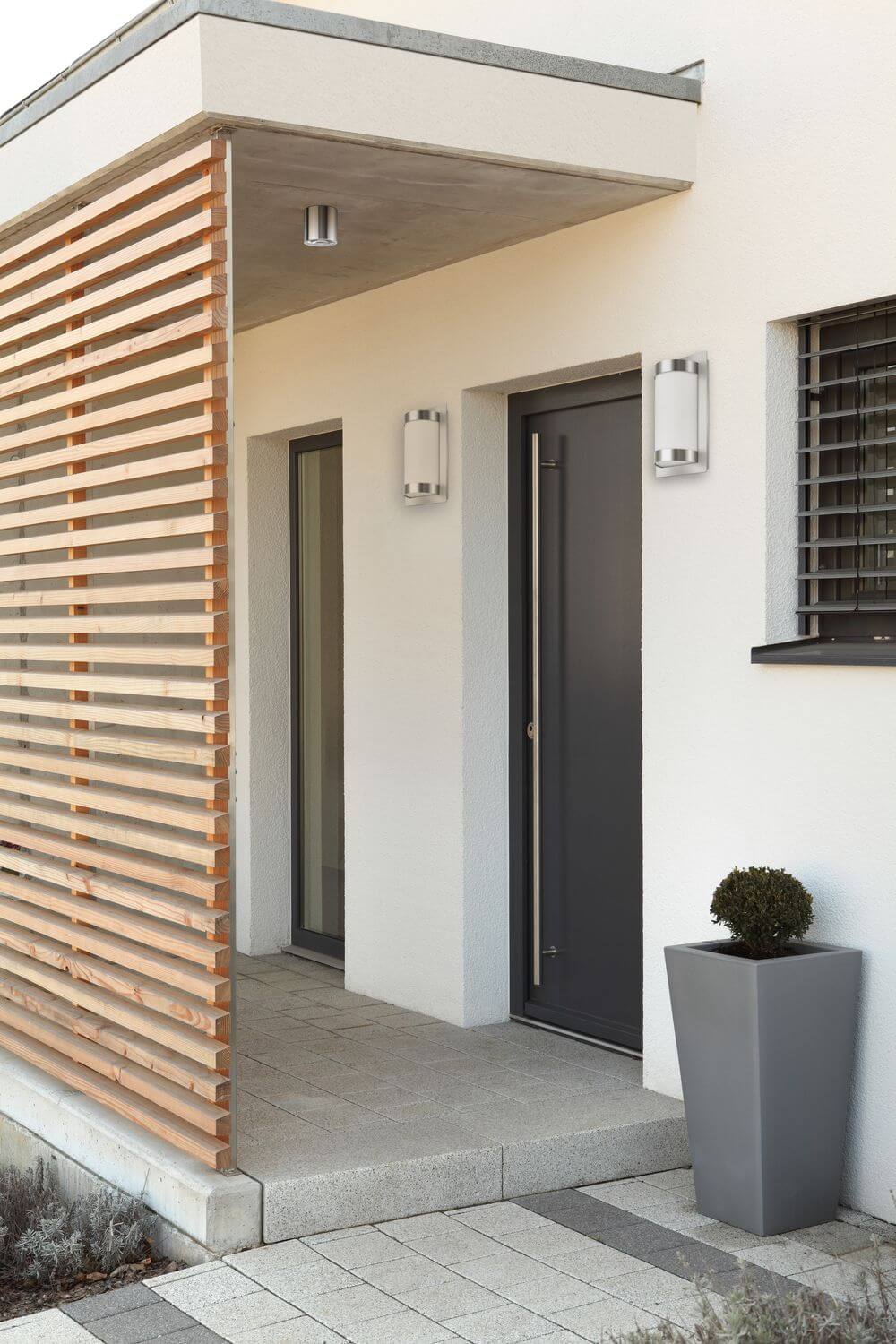 Plan rapproché de l'entrée moderne montrant les appliques inox sur façade blanche