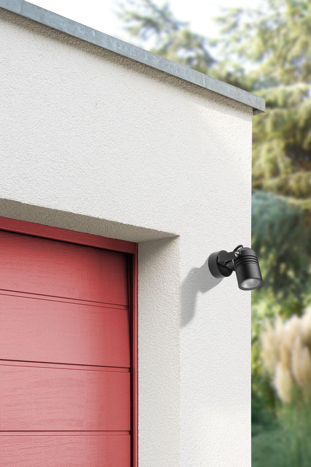 Vue rapprochée du spot mural orientable installé sur une façade extérieure crème