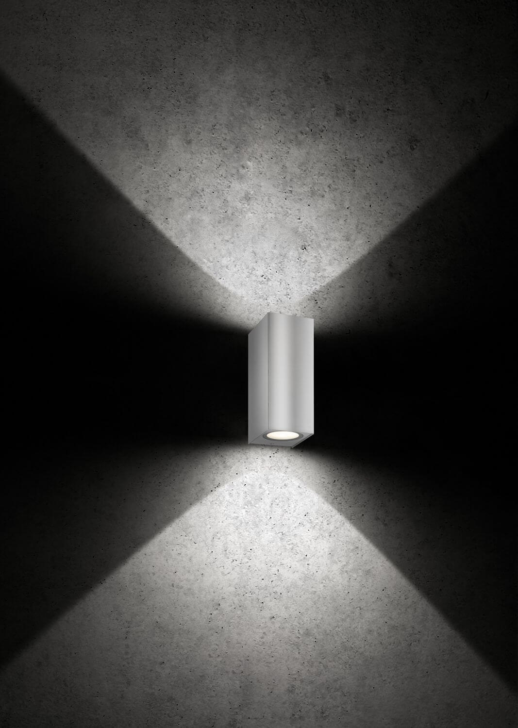 Vue rapprochée de l'applique inox éclairée sur un mur sombre