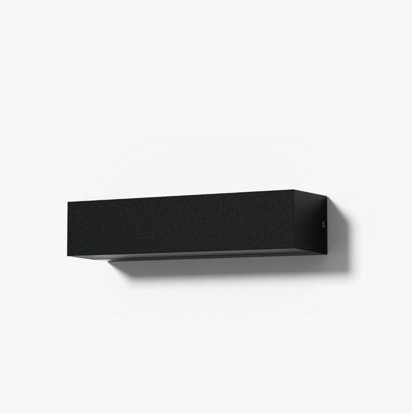 Mise en ambiance sur mur blanc, ombre portée sous le boîtier noir