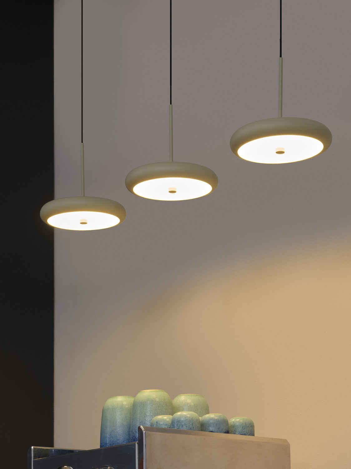 Détail de trois abat-jours ronds allumés, vus de près au-dessus de vases décoratifs.