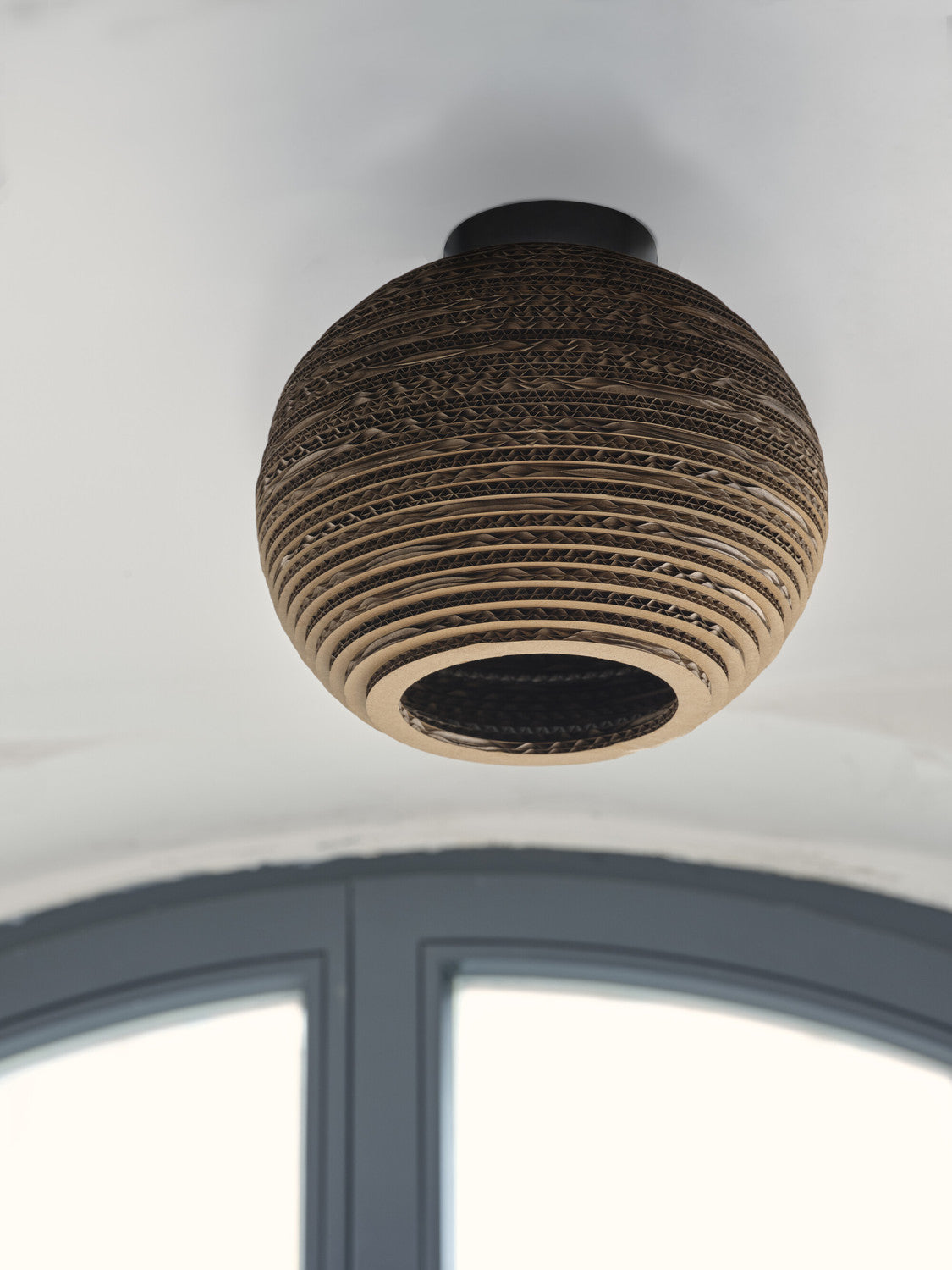 Vue de dessous du plafonnier en carton fixé au plafond blanc.
