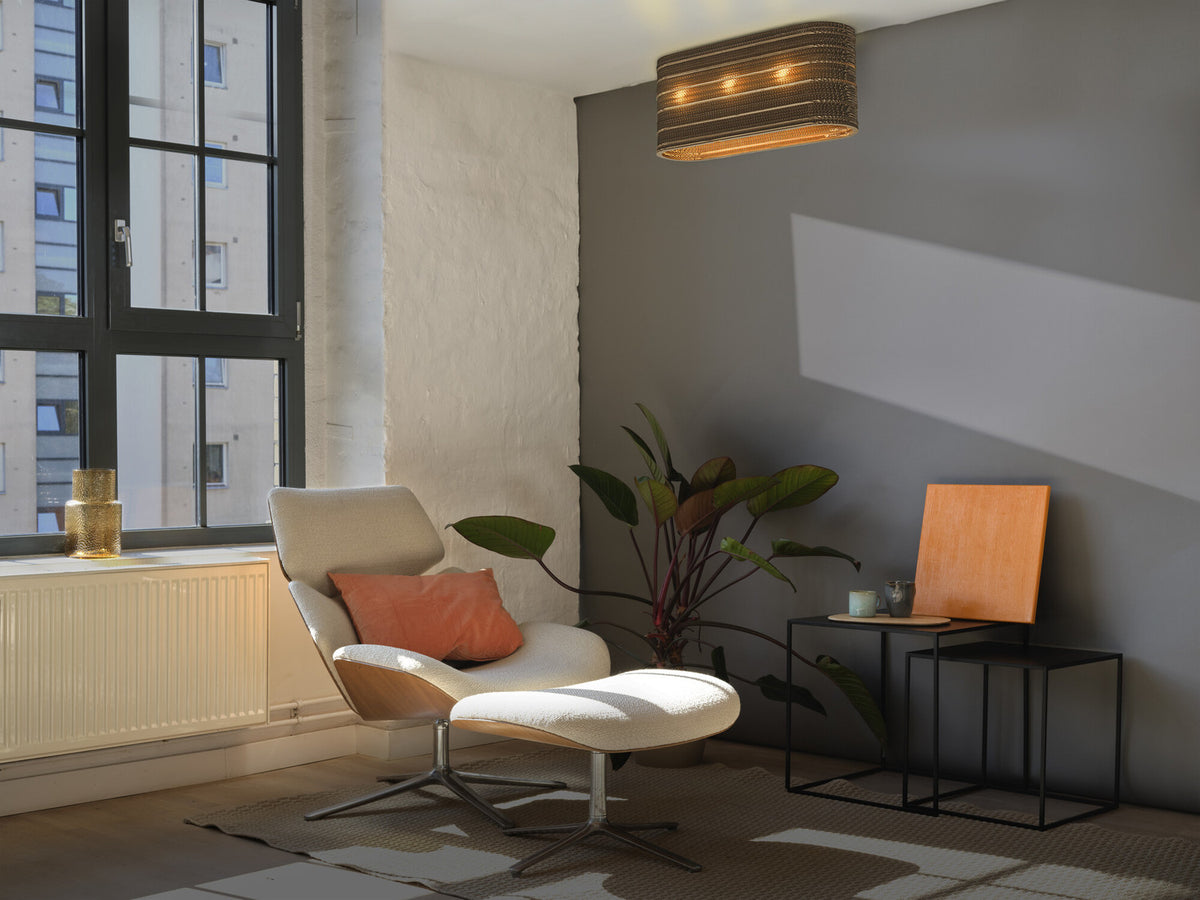 Plafonnier allumé dans un salon moderne avec fauteuil, plante et table basse