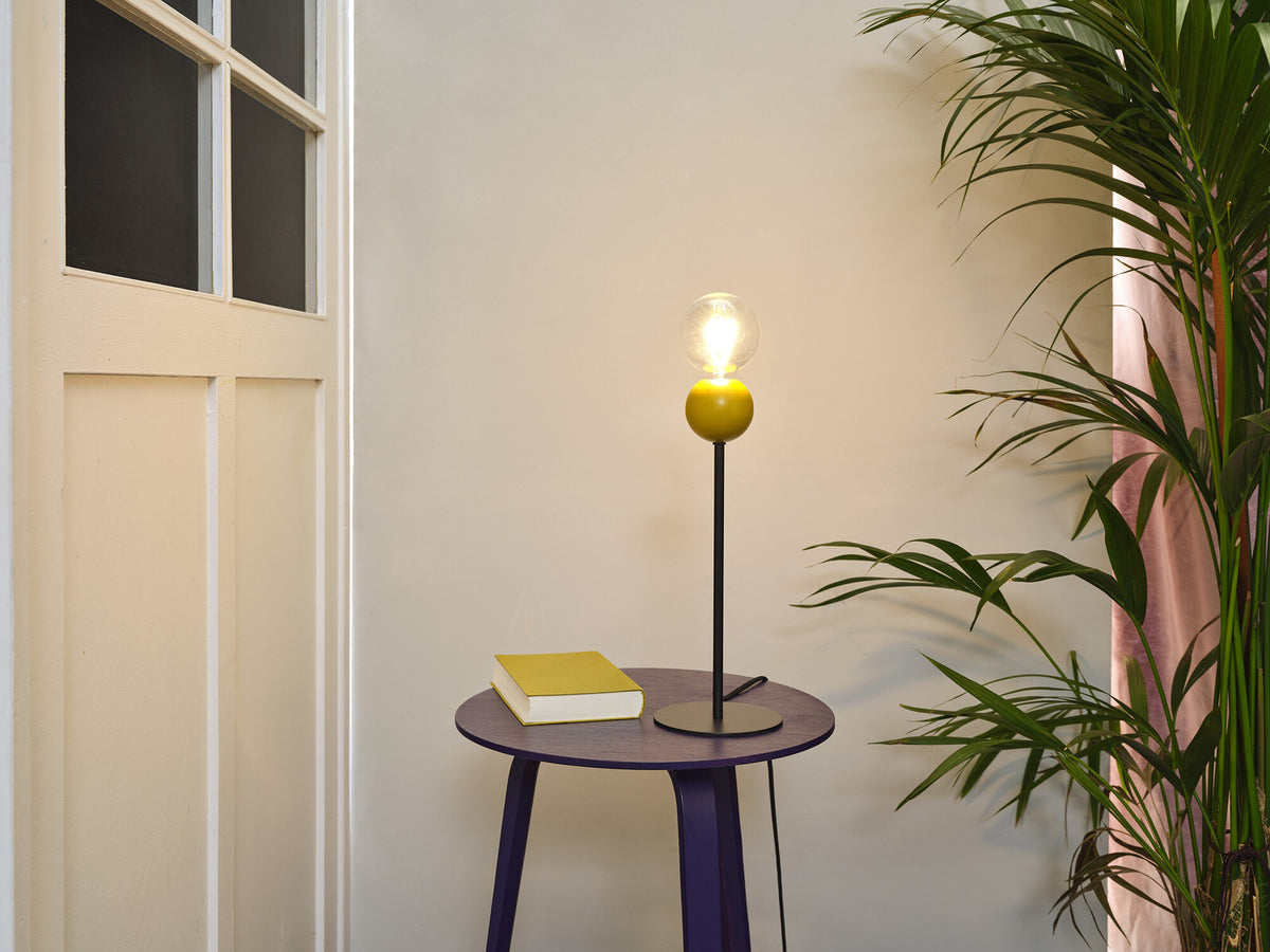 Lampe jaune sur une table d'appoint violette près d'un livre