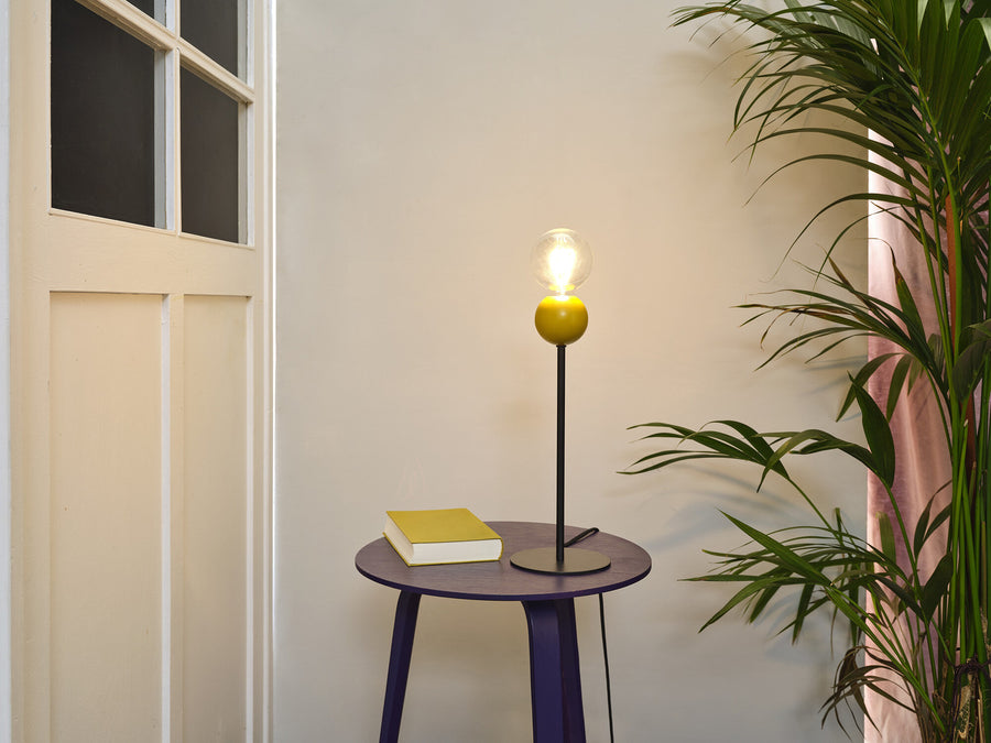 Lampe jaune sur une table d'appoint violette près d'un livre
