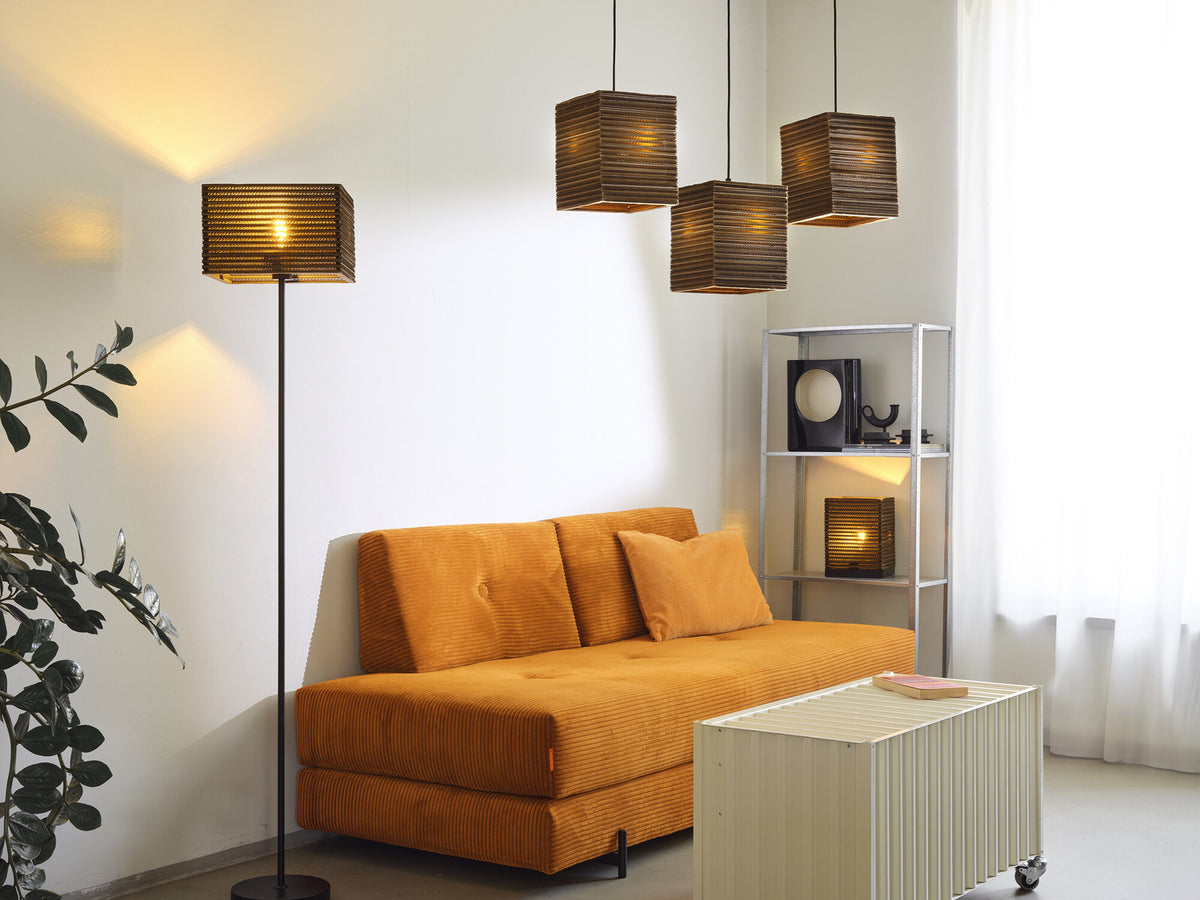 Lampadaire et suspensions carrées au-dessus d'un canapé orange, dans un salon.