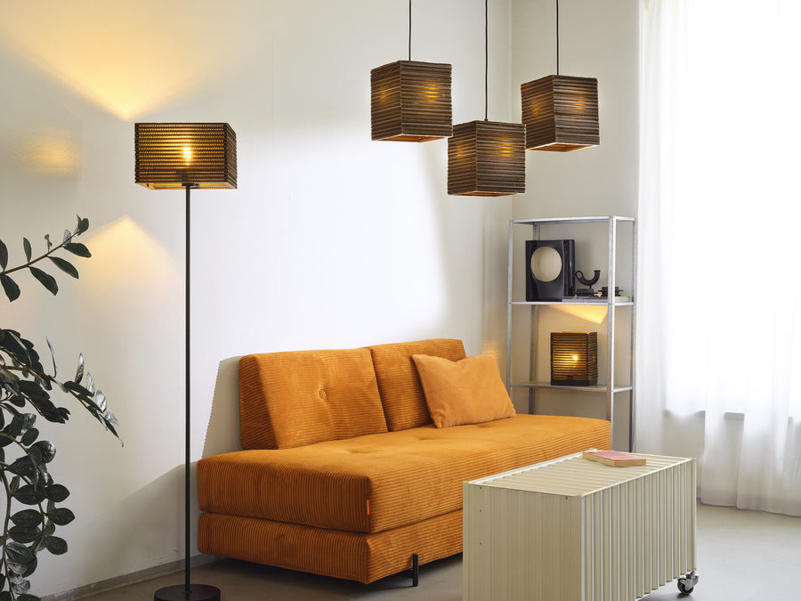 Lampadaire et suspensions carrées au-dessus d'un canapé orange, dans un salon.