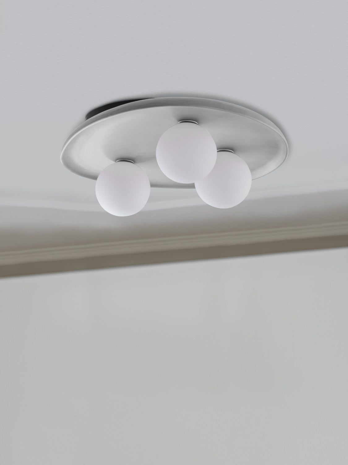 Vue rapprochée du plafonnier fixé au plafond, plateau ovale et trois globes blancs
