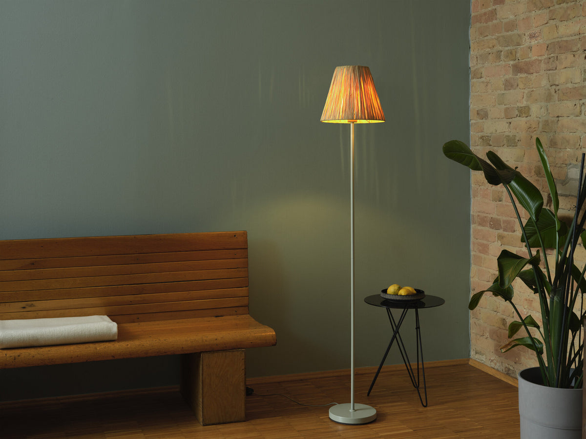 Lampadaire vert allumé dans pièce avec banc bois, mur vert et brique