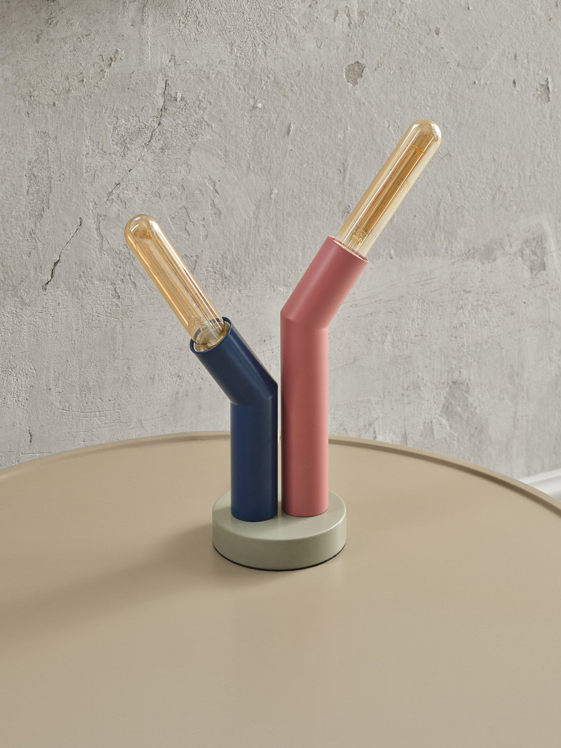 Détail des deux bras tubulaires allumés, bleu et rose, sur base grise posée.