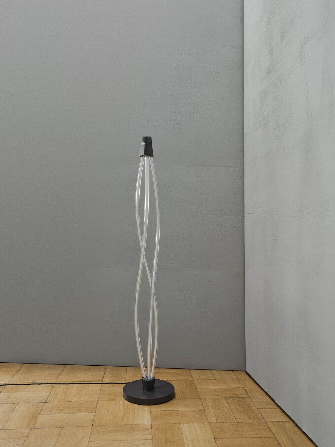 Lampadaire Swirl éteint dans un coin, base noire sur parquet clair.