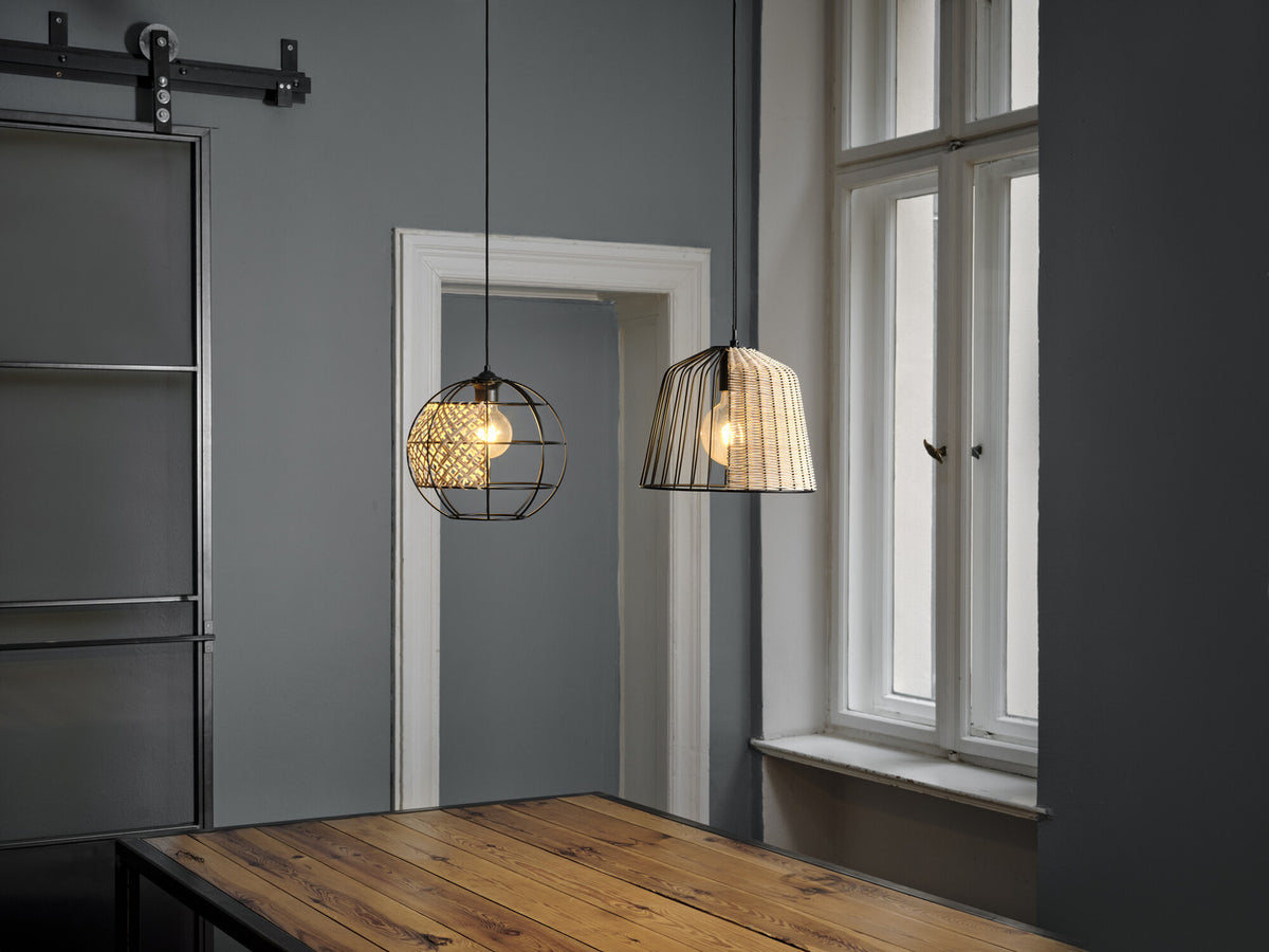 Deux suspensions allumées au-dessus d'une table en bois dans un intérieur gris.