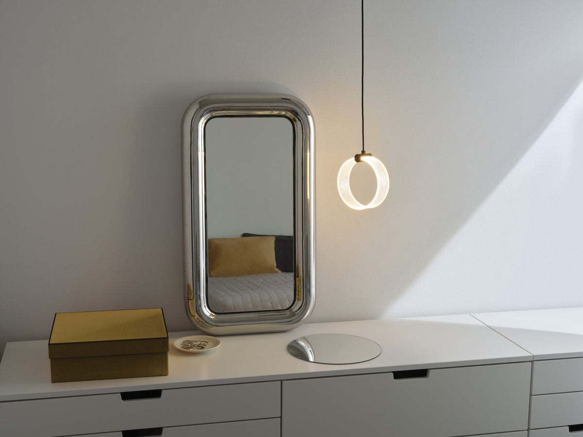 Ambiance chambre avec miroir reflétant un lit et suspension anneau suspendue