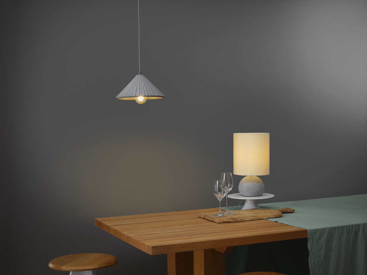 Ambiance repas avec suspension cône allumée au-dessus d'une table en bois et verres.